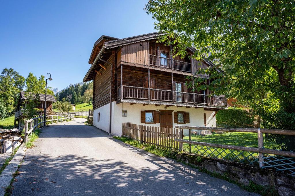 uma casa velha com uma cerca ao lado de uma estrada em Cuore delle Dolomiti em Tonadico