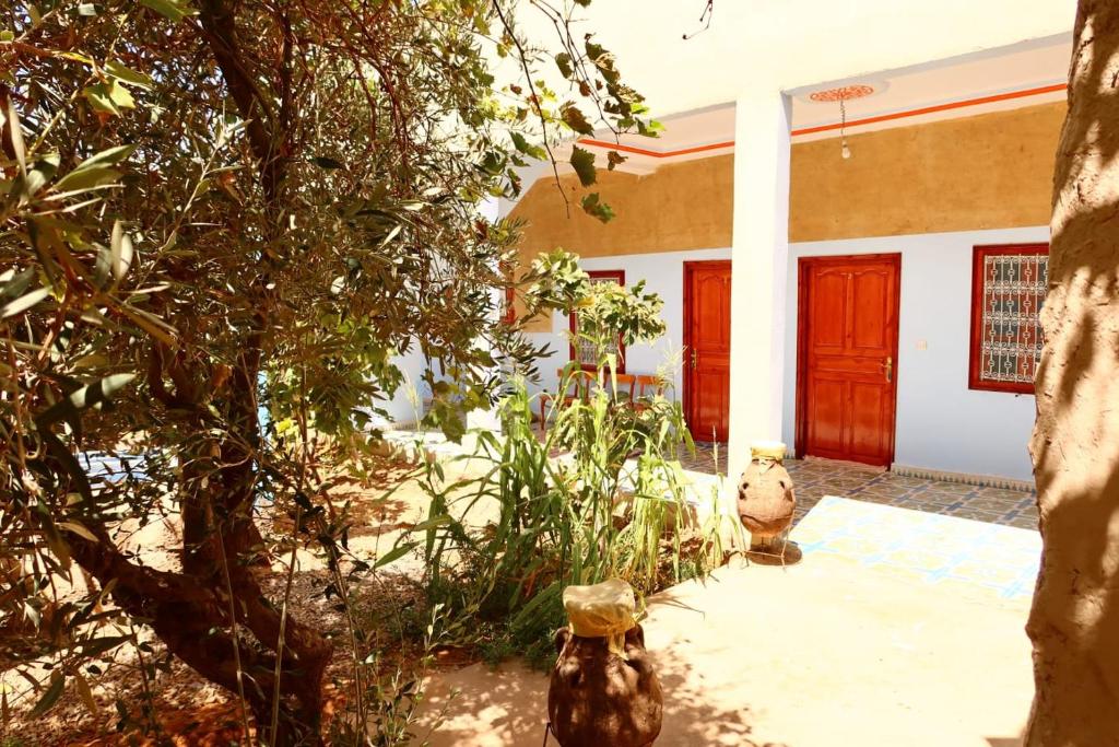 een huis met een rode deur en een boom bij gîte d'étape ziz oasis in Achbarou