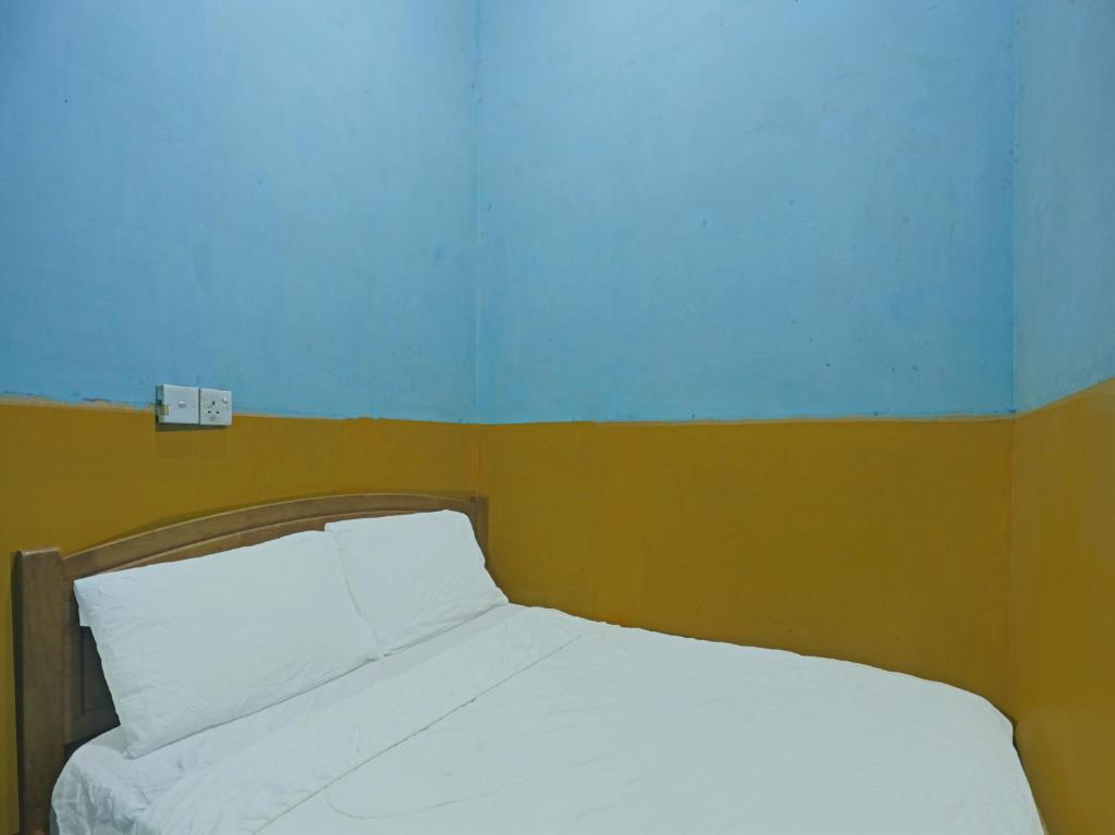 a bedroom with a white bed with a blue wall at SPOT ON 92985 Mitra Homestay in Nagoya