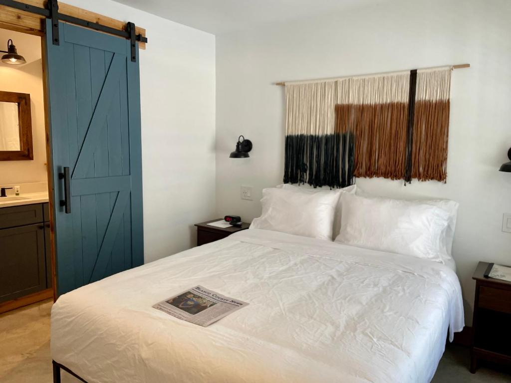 a bedroom with a white bed with a blue door at Blanco County Inn & Guesthouses in Blanco