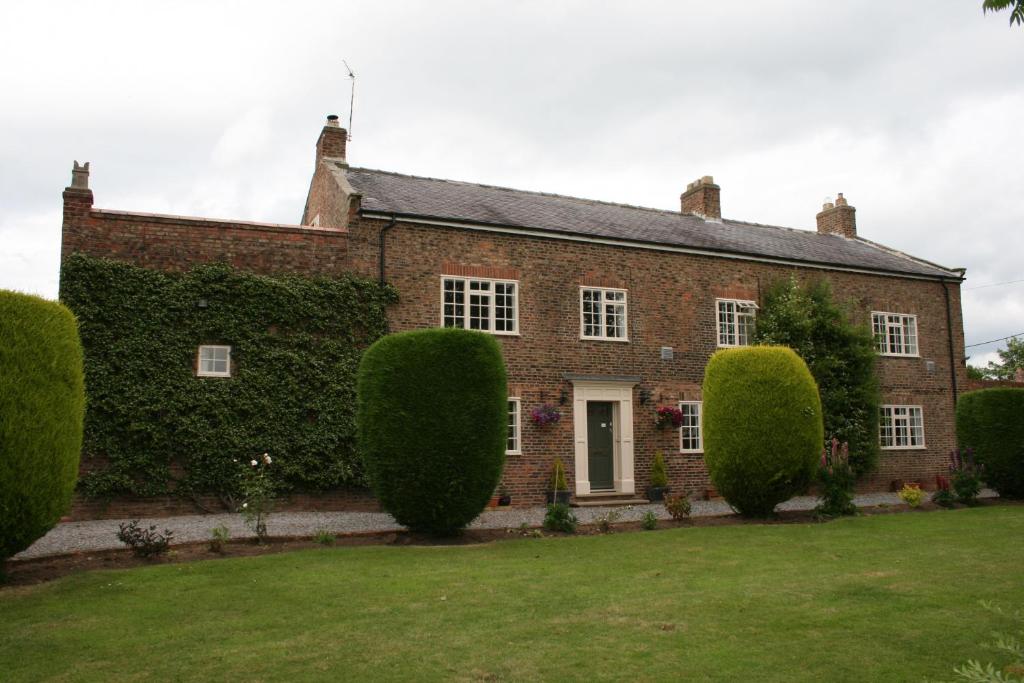a large brick house with bushes in front of it at The Manor Guest House in Linton on Ouse