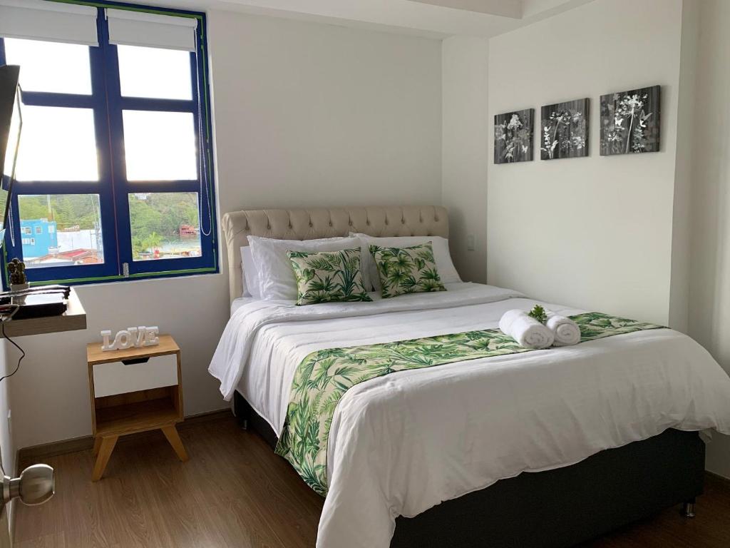 - une chambre avec un grand lit et une fenêtre dans l'établissement Apartamentos San Jose vistal al lago, cerca del parque. Guatape., à Guatapé