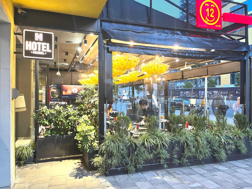 un restaurante con plantas frente a una tienda en HOTEL NOBEL CENTER en Tirana