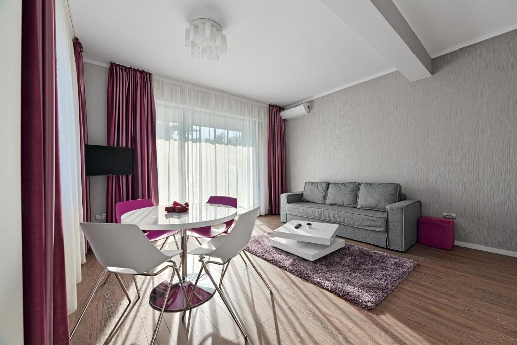 een woonkamer met een tafel en een bank bij Tomis Garden Aparthotel Mamaia in Mamaia