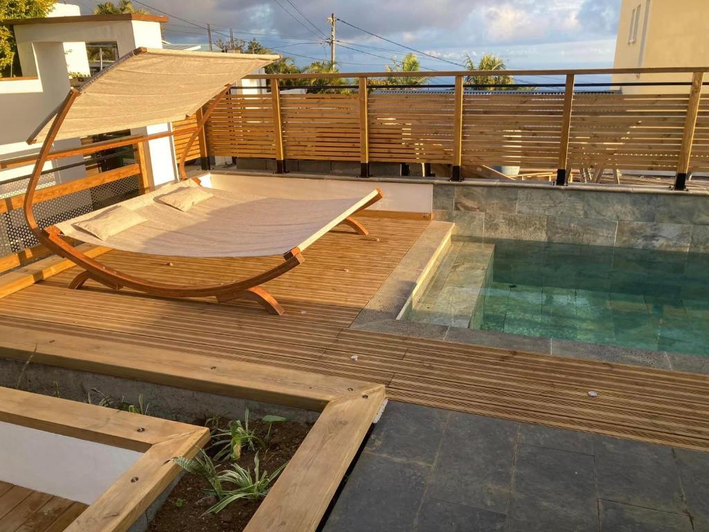a wooden deck with a chair and a swimming pool at Résidence Le Panorama 1 in Petite Île