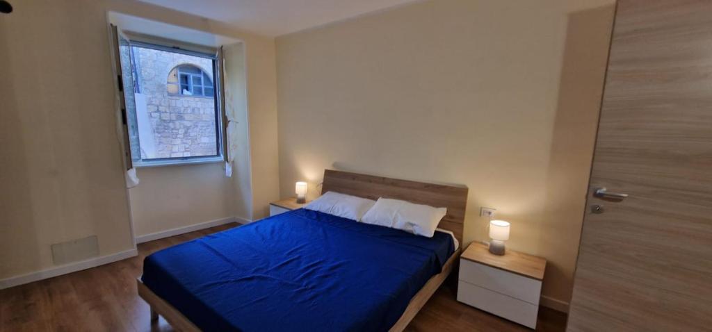 a bedroom with a bed with blue sheets and a window at Casa Torri in Tarquinia
