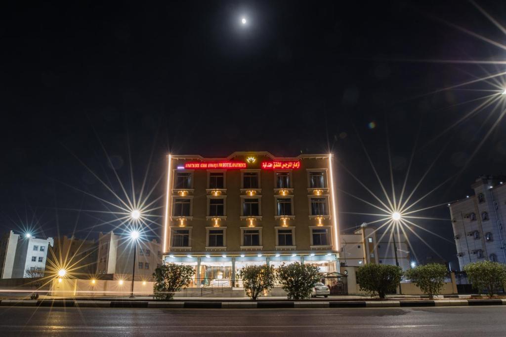um hotel com uma placa em cima à noite em أزهار النرجس للشقق الفندقية em Umm al Khashab
