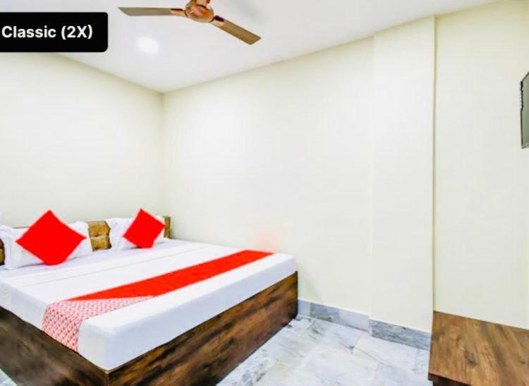 Schlafzimmer mit einem Bett mit roten Kissen und einer Decke in der Unterkunft Hotel Somnath Guest House ! Puri in Puri