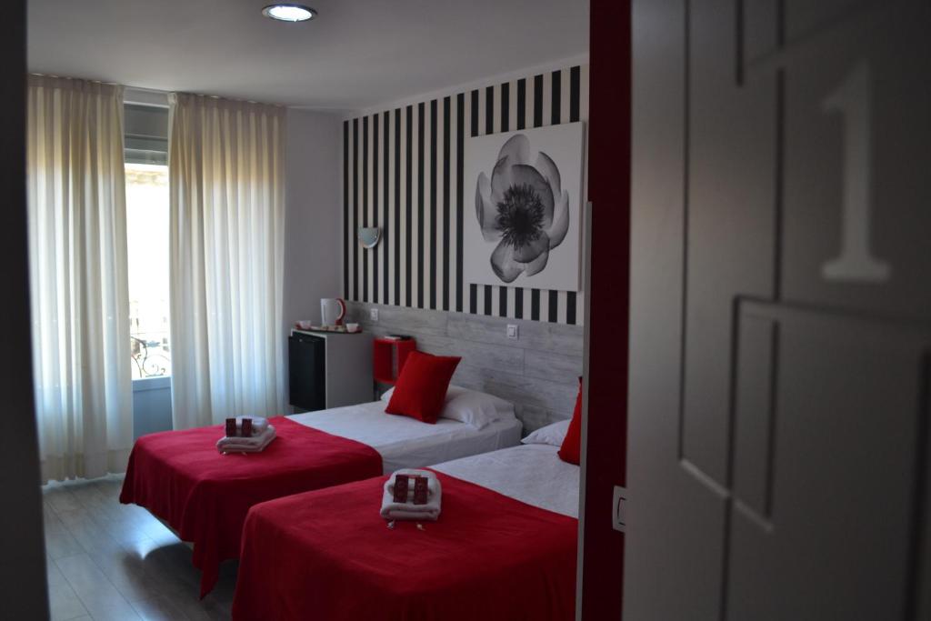 Habitación de hotel con 2 camas con sábanas rojas en Hostal Madrid Sol, en Madrid