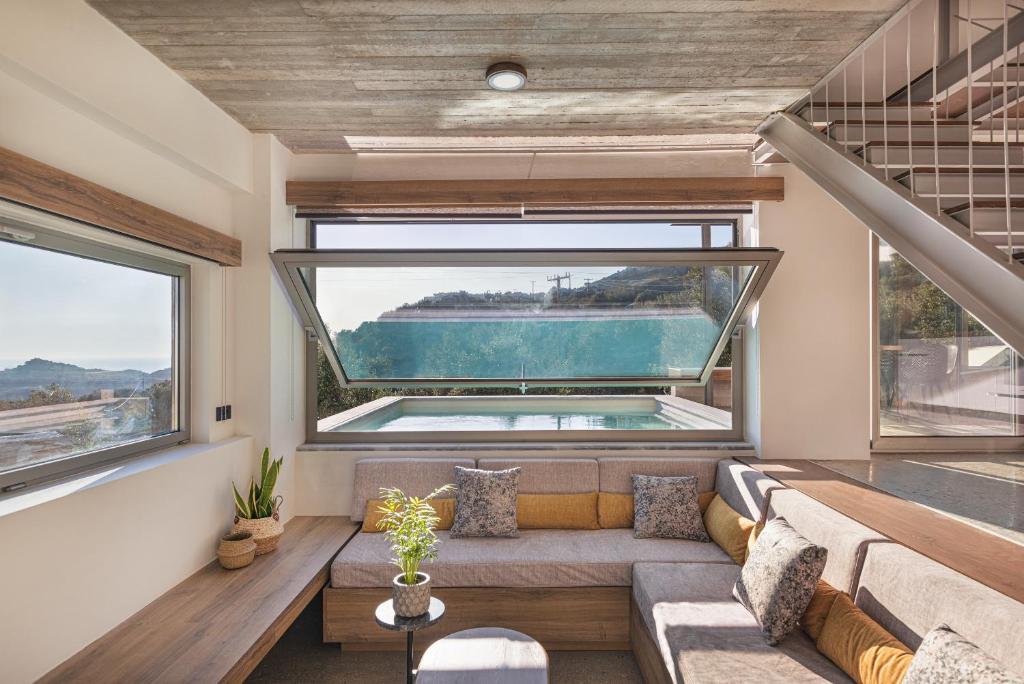 Una sala de estar con un sofá y una ventana grande. en New Modern Villa Domus Rodia with private pool & BBQ, 4km from nearest beach, en Marioú