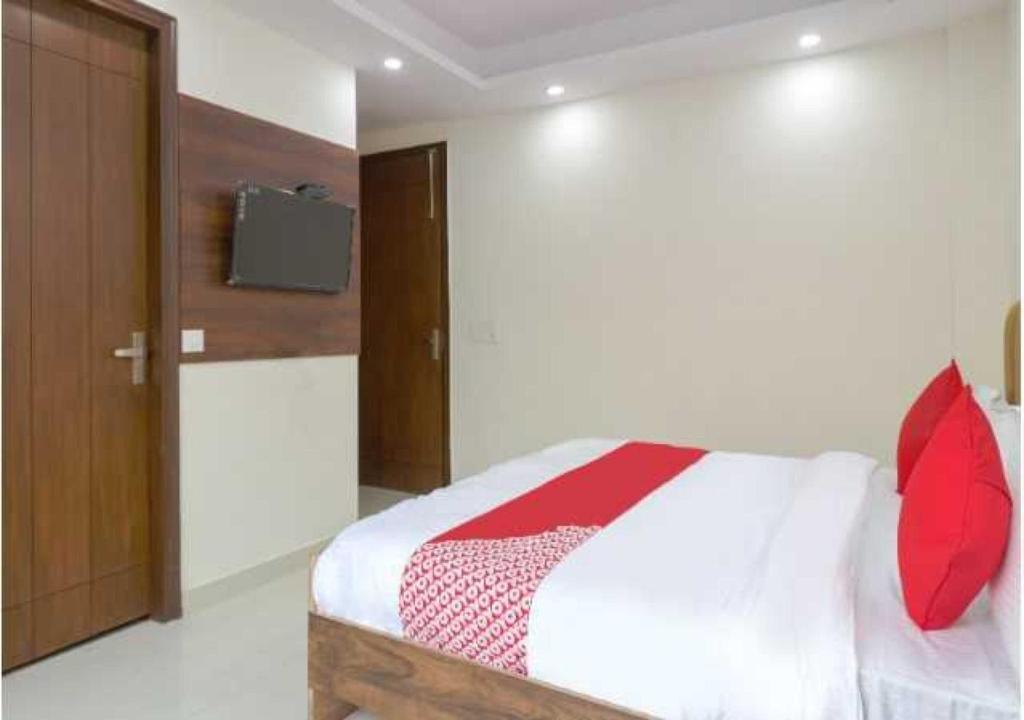 1 dormitorio con 1 cama con almohadas rojas y TV en Flagship Leisurrestay, en Nueva Delhi