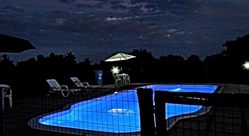 una piscina notturna con ombrellone di CASA MAR A VISTA a Cumuruxatiba
