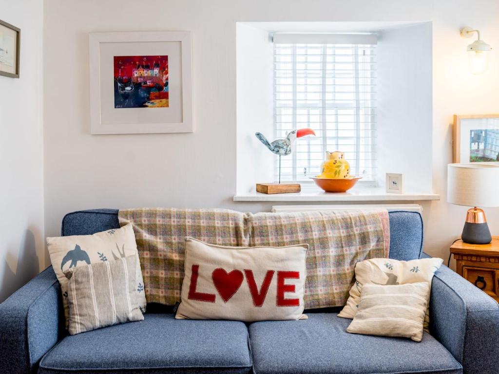 ein blaues Sofa mit Liebeskissen im Wohnzimmer in der Unterkunft Pass the Keys Lovely Old Fishermans Cottage in Anstruther
