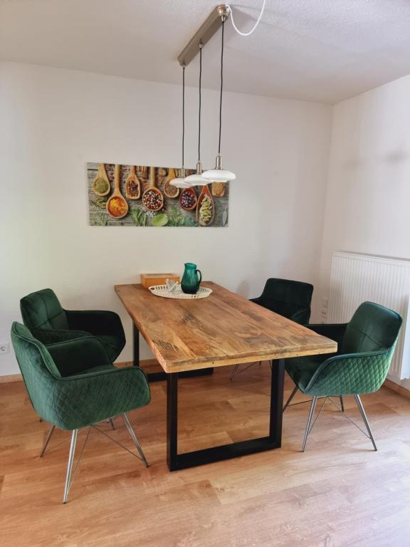 ein Esszimmer mit einem Holztisch und grünen Stühlen in der Unterkunft Wohlfühloase in Sankt Wendel