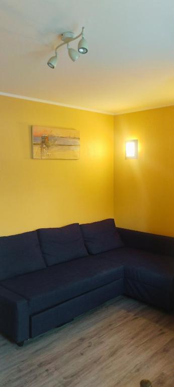 a blue couch in a room with a yellow wall at Home Sweet Home in Bouglainval