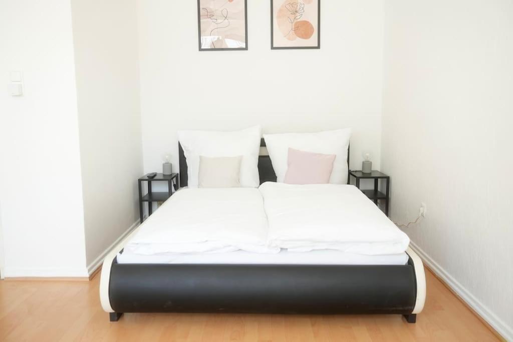 1 cama con sábanas blancas y almohadas en una habitación en Stadtoase Wohnung nahe Hauptbahnhof, en Coblenza