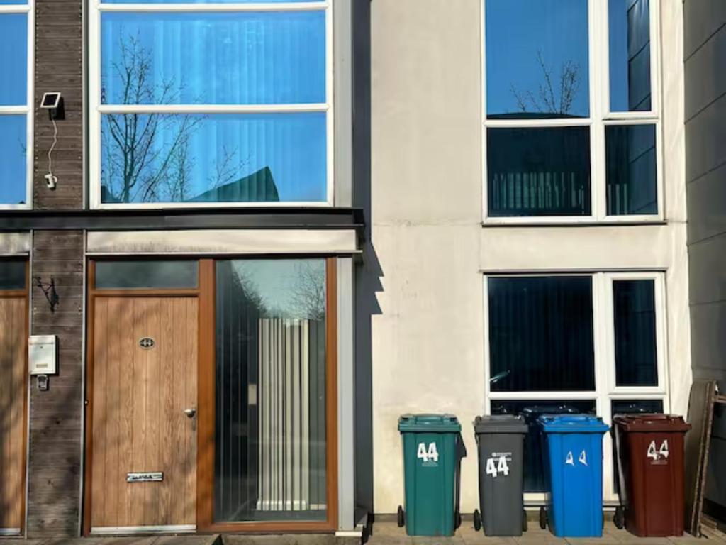 ein Gebäude mit einer Holztür und zwei Mülltonnen in der Unterkunft Crystal Home in Manchester