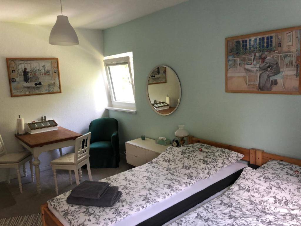 1 Schlafzimmer mit 2 Betten, einem Schreibtisch und einem Spiegel in der Unterkunft Stadtvilla-Apartment mit Parkblick und bester Verkehrsanbindung in Bremerhaven