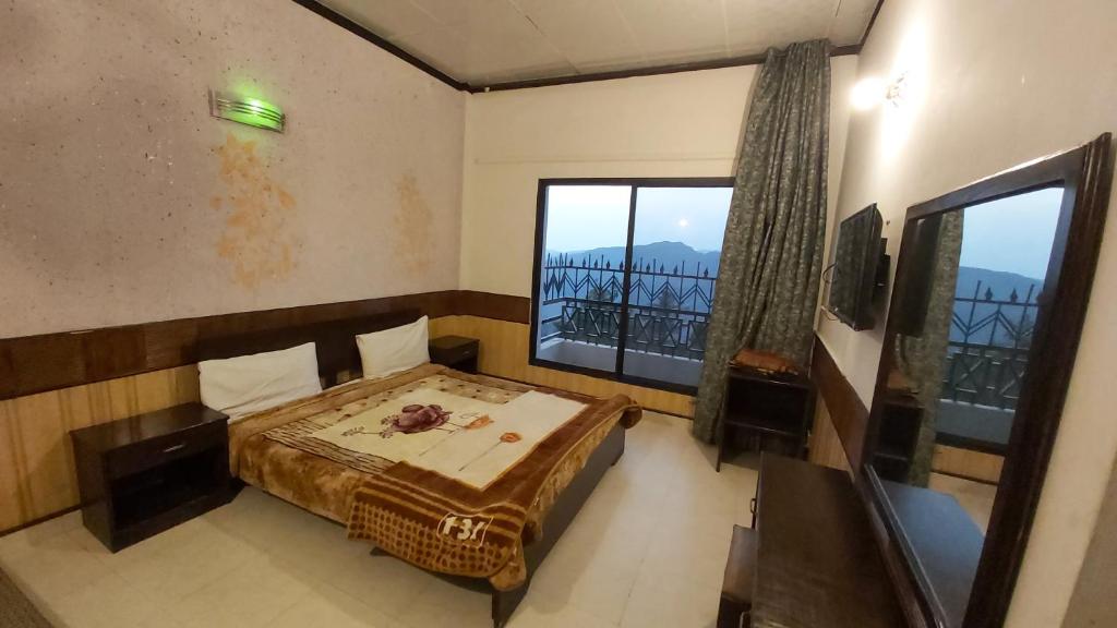 a bedroom with a bed and a large window at Mount Heaven Hotel Murree in Murree