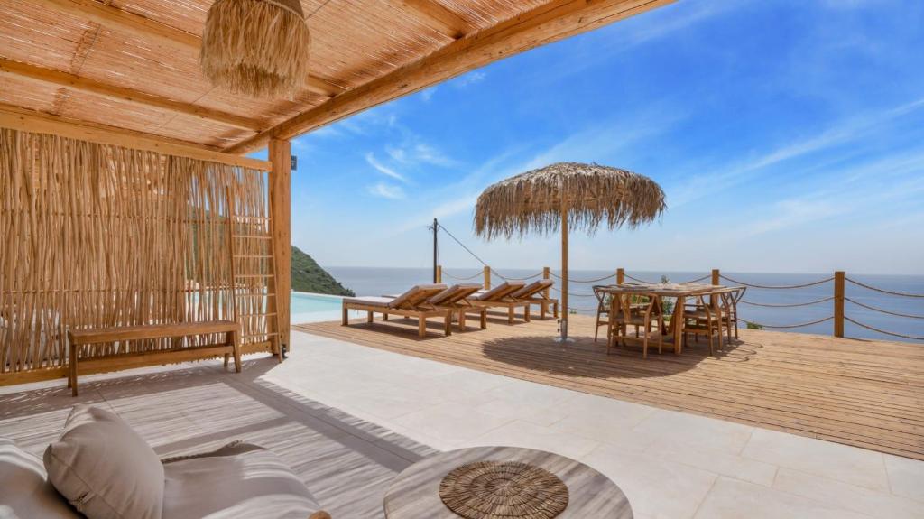 a patio with a table and chairs and the ocean at Eunoia Porto Katsiki in Áyios Nikólaos Nirás