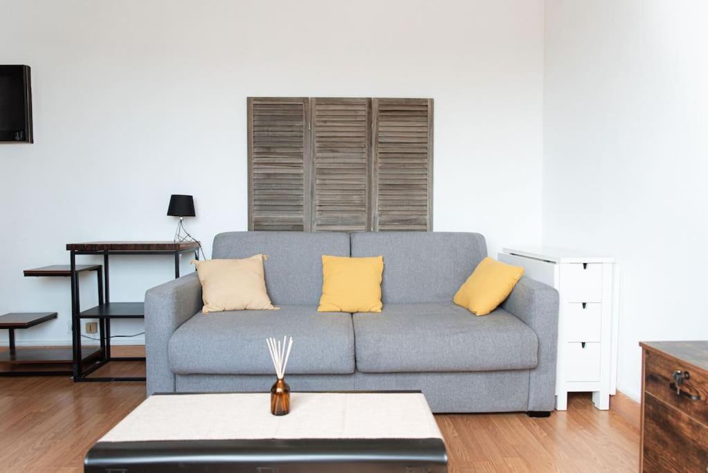 sala de estar con sofá azul y almohadas amarillas en Studio Gare Saint Jean, en Burdeos