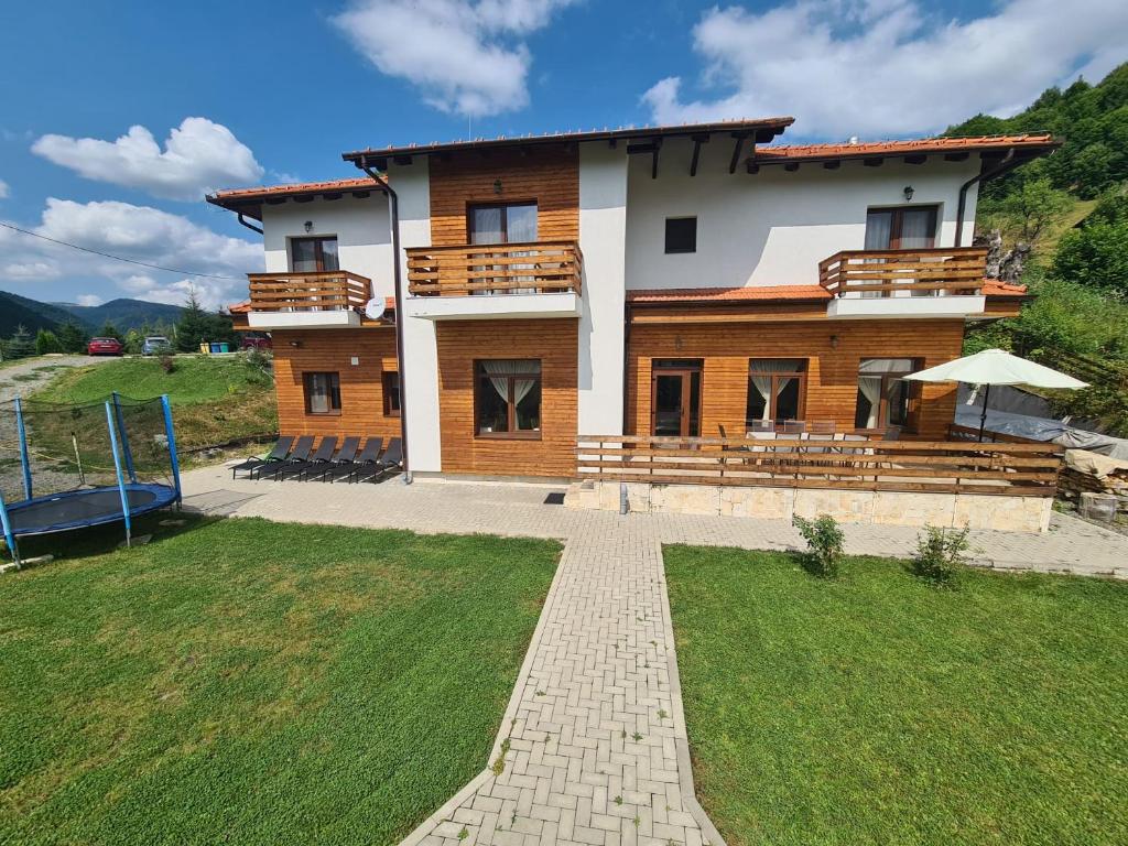 una casa en una colina con un patio de hierba en APUSENI HOLIDAYS, en Răchiţele