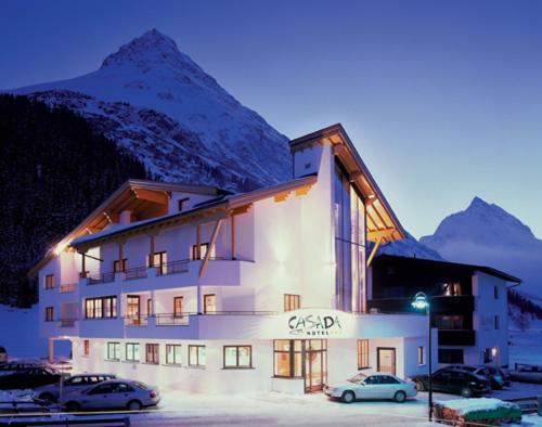 a building with cars parked in front of it with a mountain at Ferienwohnung Florina in Galtür