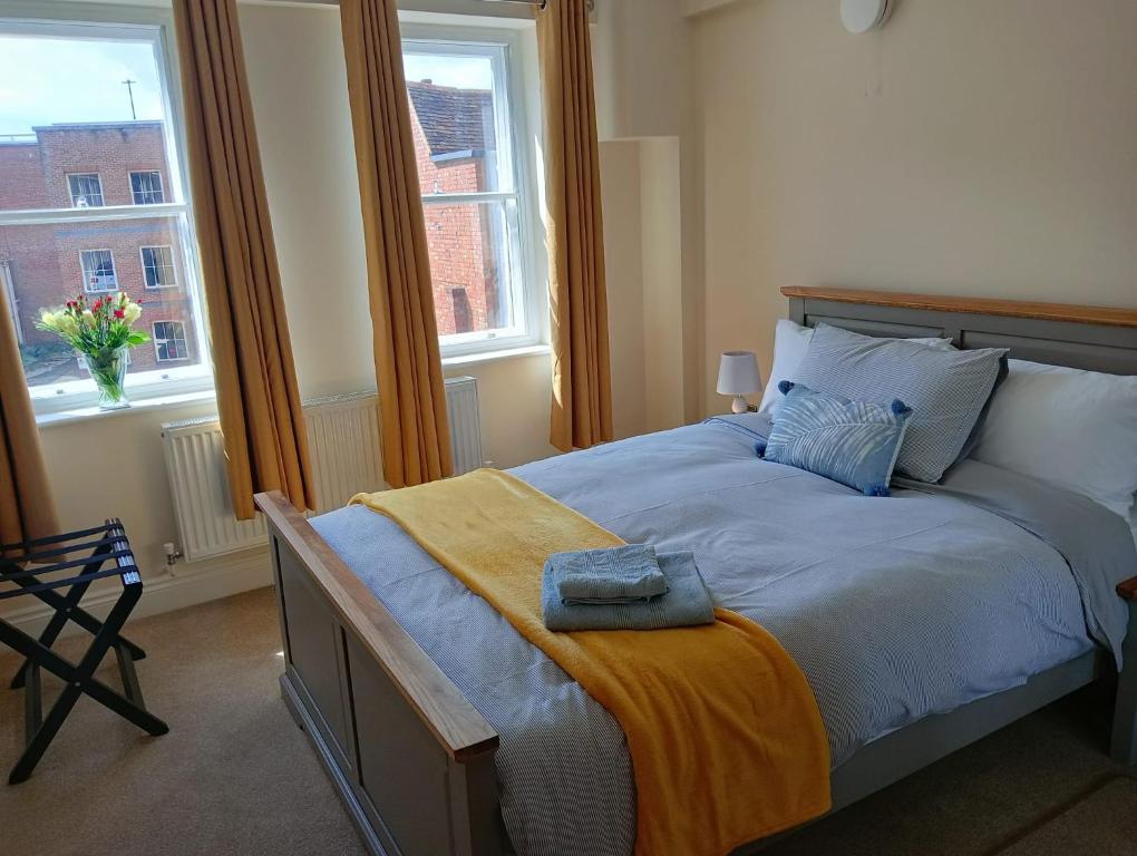 a bedroom with a large bed with two windows at Barchester House Apartment Standard in Salisbury