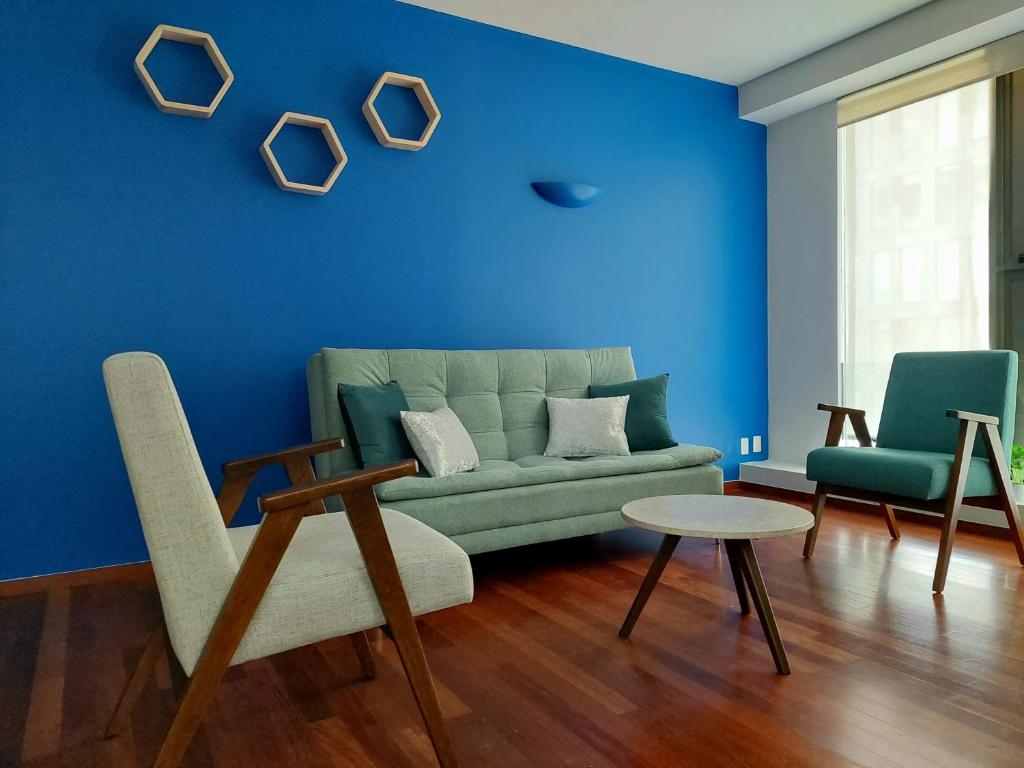 Sala de estar azul con sofá y 2 sillas en Punto Alameda - Reforma, en Ciudad de México
