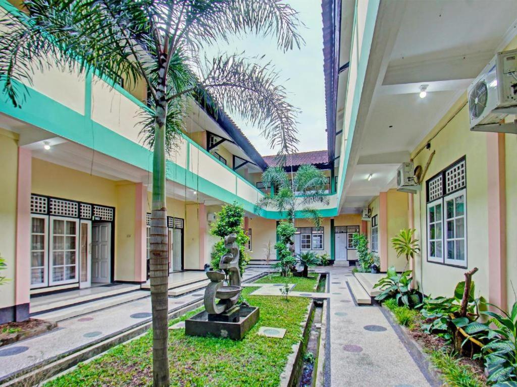 une cour avec des palmiers dans un bâtiment dans l'établissement Unram Guest House, à Tjakranegara