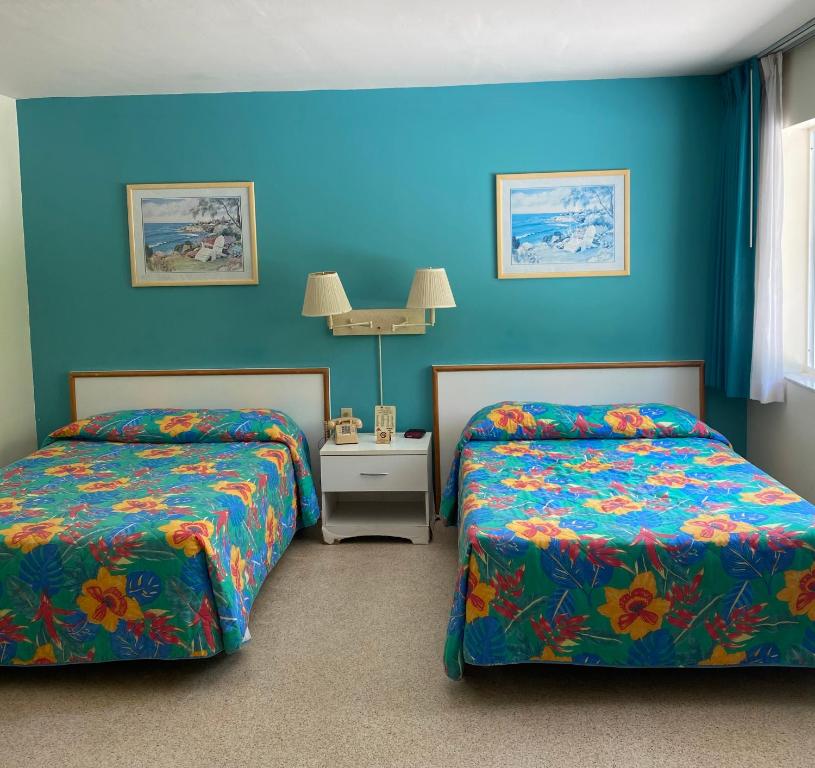 2 łóżka w pokoju z niebieskimi ścianami w obiekcie Silver Sands Beach Resort w Miami