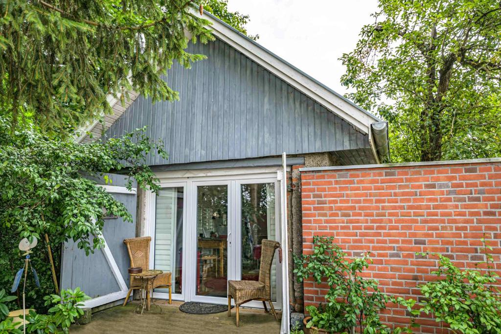 uma casa com um pátio com cadeiras e uma parede de tijolos em Zimmer in Ferienhäusschen am See / Karstädt em Karstädt