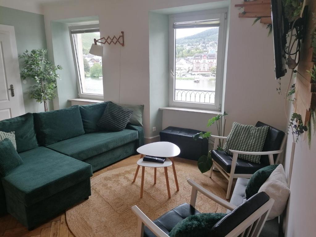 a living room with a green couch and chairs at Voll ausgestattete Wohnung mit Moselblick in Alf