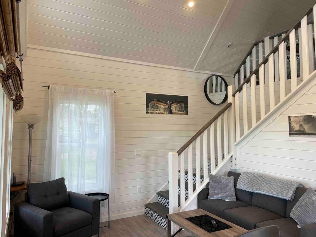 uma sala de estar com uma escada com um sofá e uma cadeira em Sunrise Loft - Beach front guest house em Sandspit