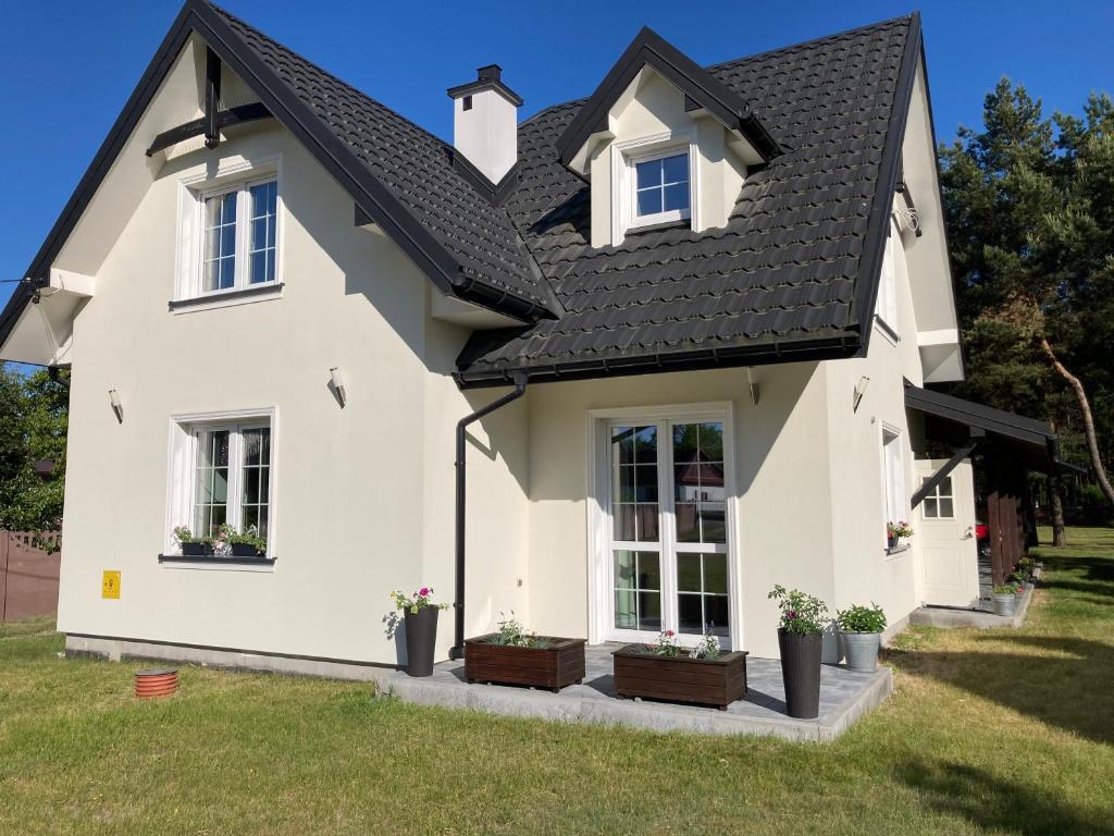 a white house with a black roof at Agroturystyka u Sylwii in Majdan Sopocki