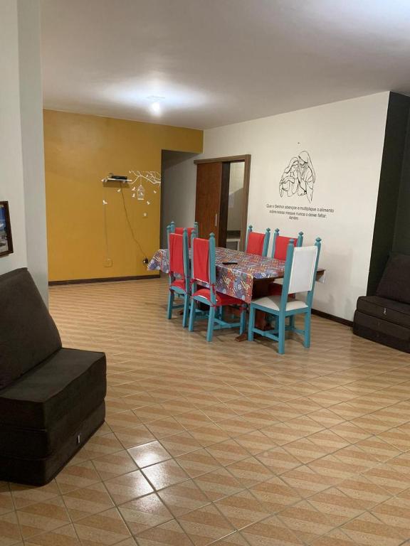 ein Esszimmer mit einem Tisch und roten Stühlen in der Unterkunft APARTAMENTO PRAIA DO MORRO, 04 QUARTOS, ATE 10 PESSOAS. in Guarapari