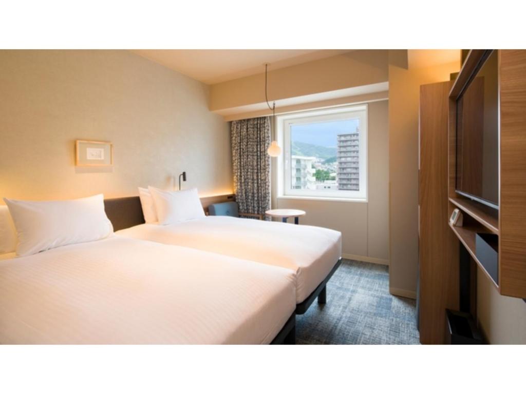 a hotel room with two beds and a window at GRIDS Premium Hotel Otaru - Vacation STAY 68537v in Otaru