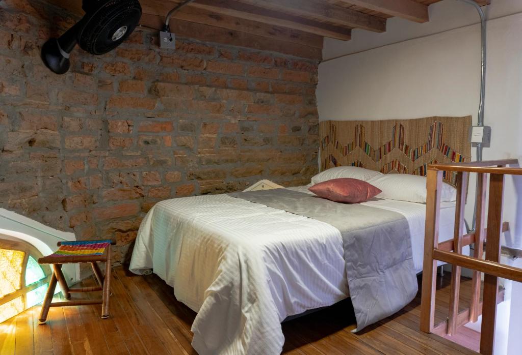 a bedroom with a bed and a brick wall at Casa Moore in Medellín