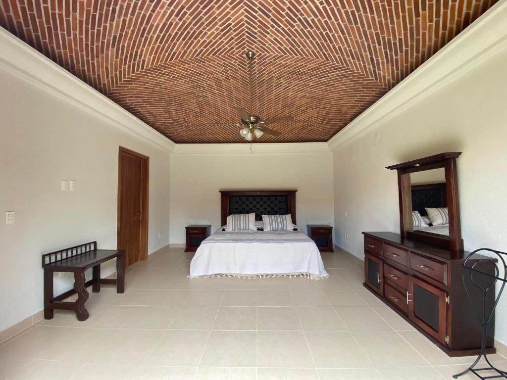 1 dormitorio con cama y techo de madera en Villa acogedora con patio estilo hacienda., en Ajijic