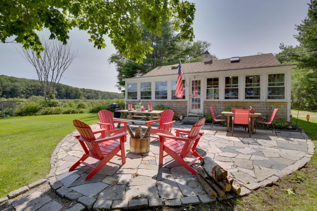 eine Terrasse mit roten Stühlen und einem Tisch vor einem Haus in der Unterkunft Waterfront Nobleboro Cottage with Kayaks and Boat Dock in Nobleboro