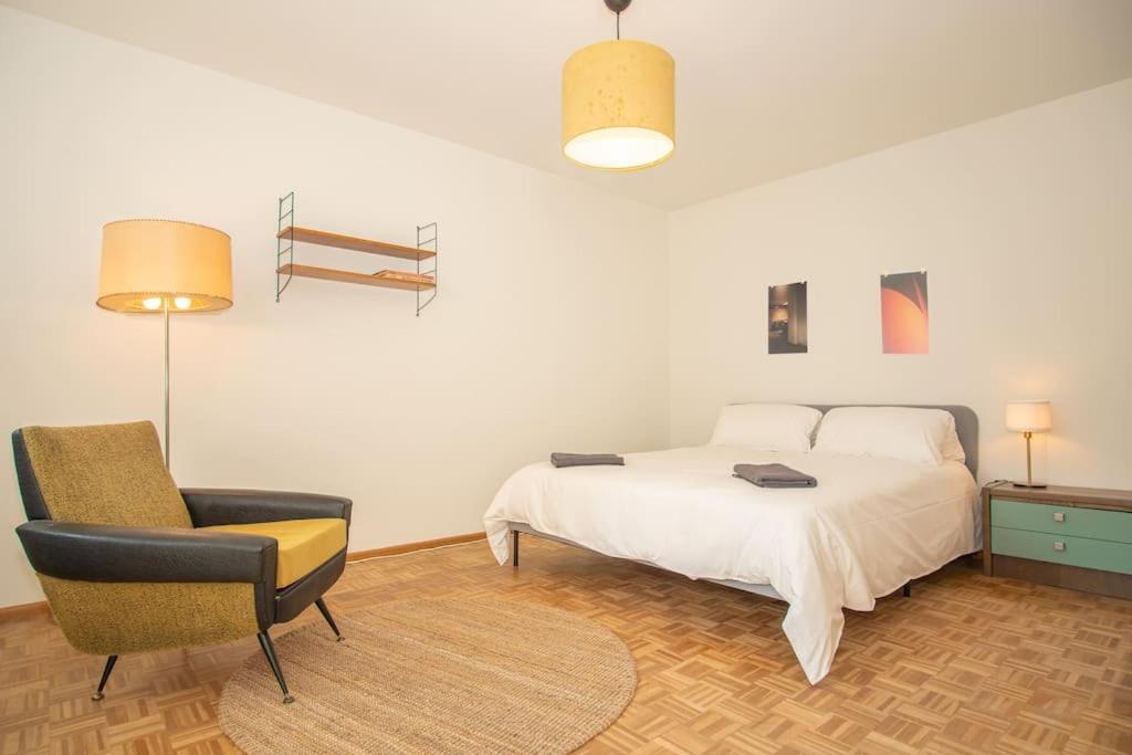 Modern 2-Bedroom Apartment in City Centre في بازل: غرفة نوم بسرير وكرسي ومصباح