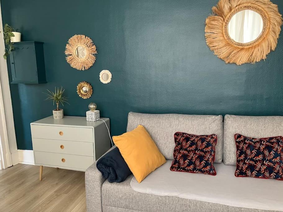 sala de estar con sofá y pared con espejos en Joli appartement à Brive la gaillarde, en Brive-la-Gaillarde