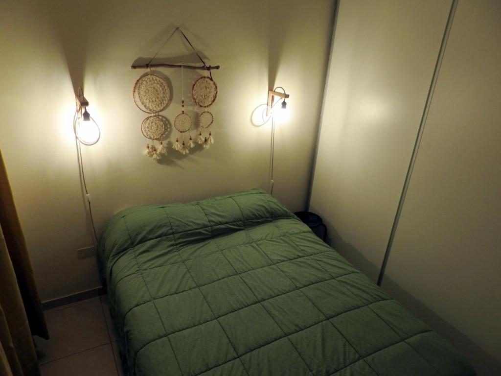 a small bedroom with two lamps and a green bed at LAS FLORES SAN JUAN in San Juan