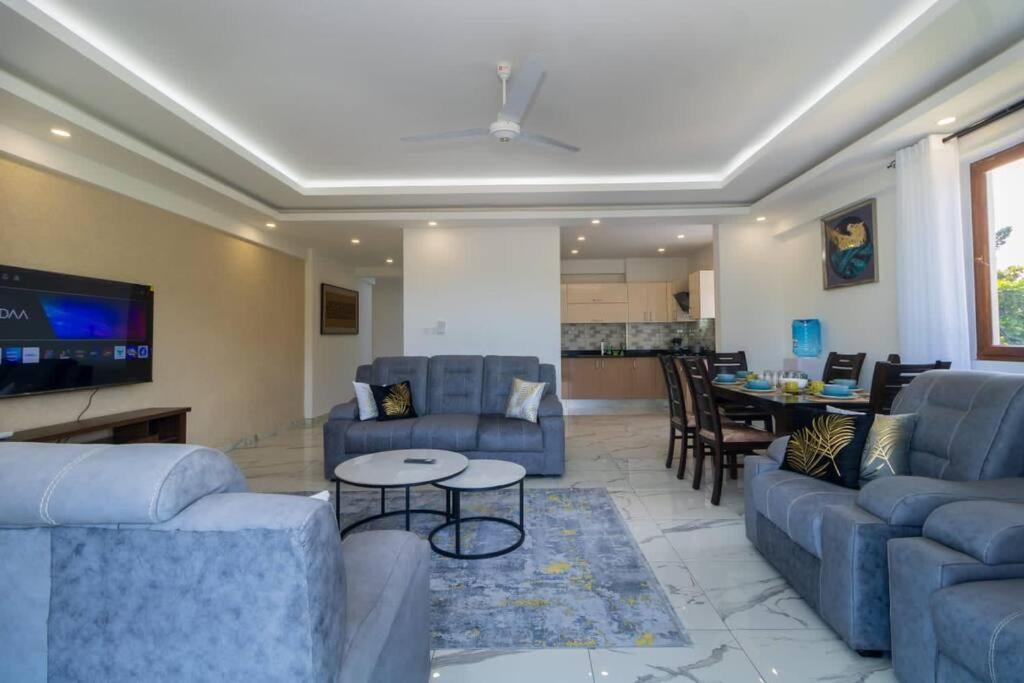 un soggiorno con divani blu e un tavolo di Sedra home@Aqua apartments a Mombasa