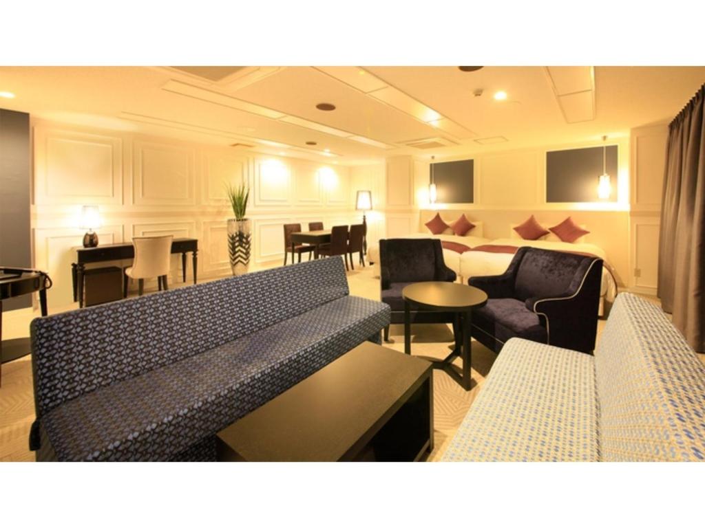 een woonkamer met banken, stoelen en tafels bij Centurion Hotel Villa Suite Fukui Ekimae - Vacation STAY 34644v in Fukui