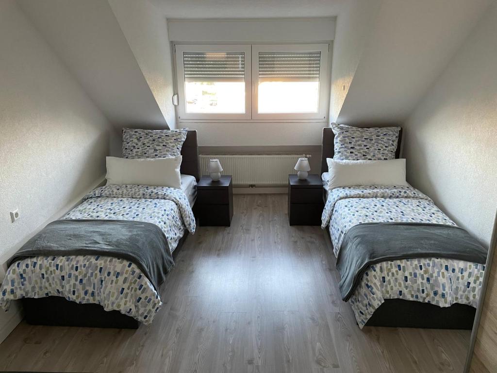 two twin beds in a room with a window at Ferienwohnung Rastatt in Rastatt