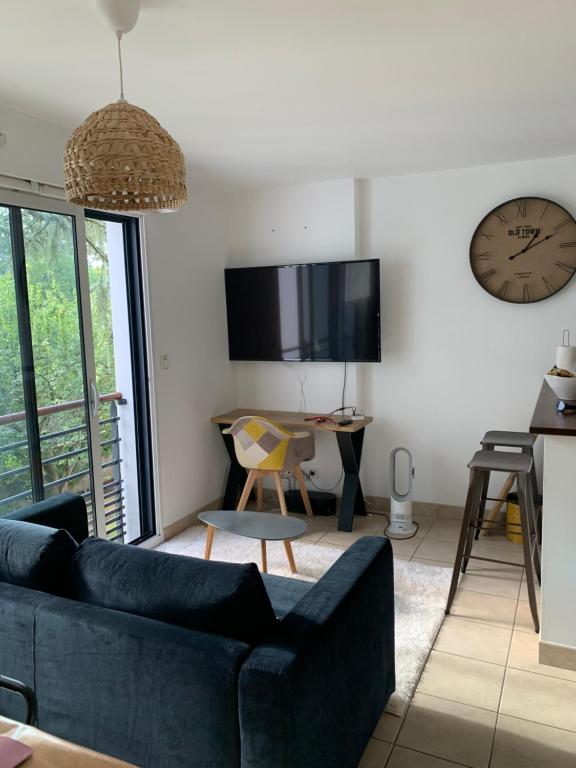 a living room with a couch and a clock on the wall at Appartement cosy jardin des plantes avec parking in Nantes