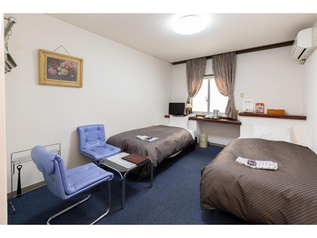 a room with two beds and two chairs and a window at Business Hotel Katsuya - Vacation STAY 62201v in Wakayama