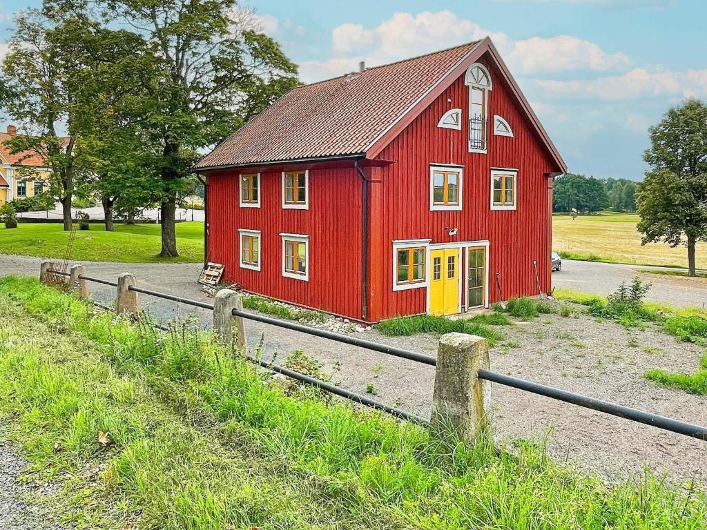 Haddebo的住宿－Holiday home HJORTKVARN III，一条红色谷仓,旁边是一条路,有一个黄色的门