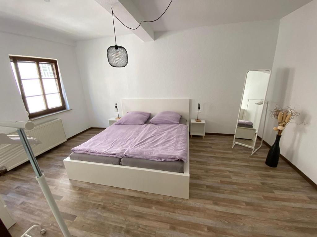 a white bedroom with a bed and a wooden floor at Weilburg-Domizil in Weilburg